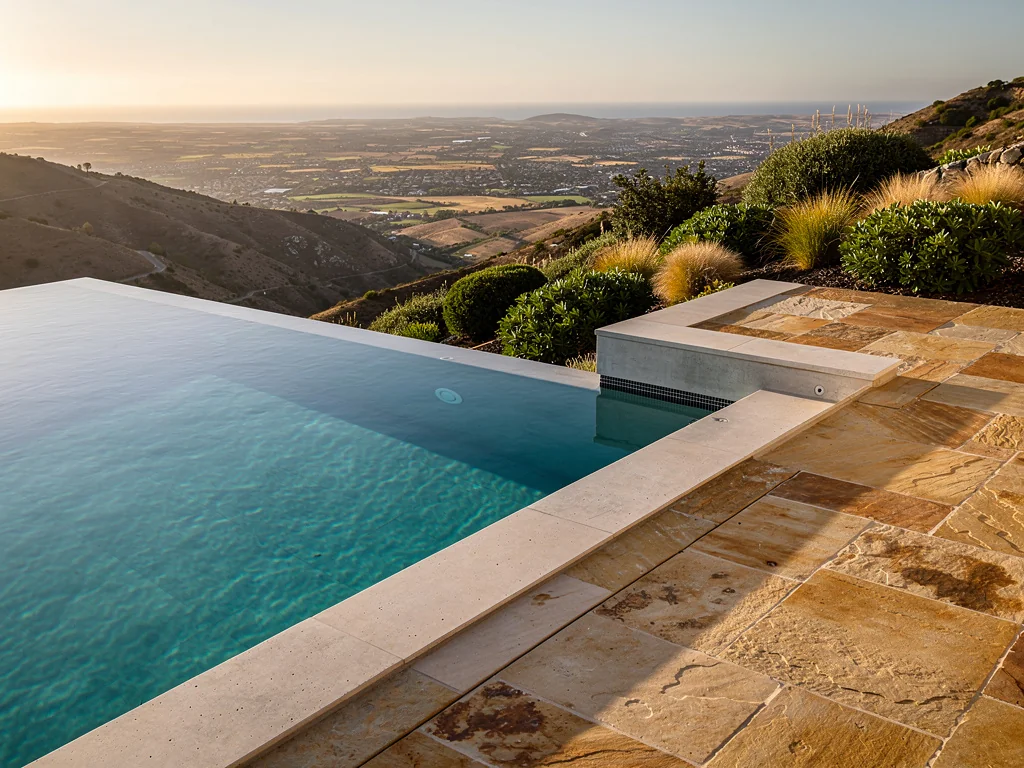 Piscine à débordement en béton dominant un jardin en pente